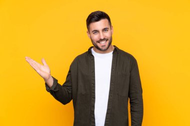 İzole edilmiş sarı arkaplan üzerinde bir adam, kopyalanmış alanı avucunun içinde tutuyor.