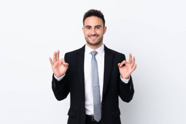Tecrit edilmiş arka planda genç bir iş adamı parmaklarıyla iyi bir işaret gösteriyor.