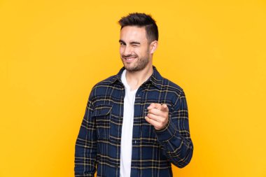 Izole sarı arka plan noktaları üzerinde genç yakışıklı adam size parmak