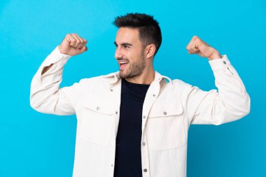 Soyutlanmış mavi arka planda genç yakışıklı bir adam zaferi kutluyor.