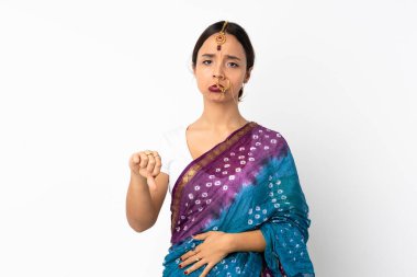Beyaz arka planda izole edilmiş genç Hintli kadın, olumsuz ifade ile baş parmağını aşağı gösteriyor.