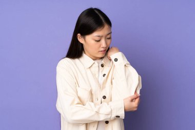 Mor arka planda dirsek ağrısı olan genç Asyalı kadın.