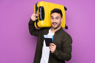 İzole edilmiş mor bir geçmişi olan genç yakışıklı bir adam. Tatilde bavul ve pasaportla.