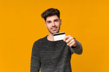 Soyutlanmış bir geçmişi olan genç bir adam kredi kartı tutuyor.