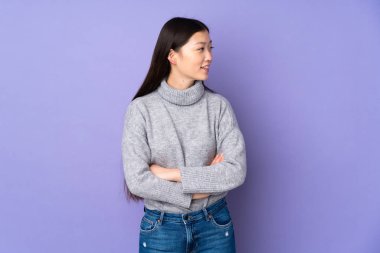 Asyalı genç bir kadın soyutlanmış arka planda, yana bakıyor ve gülümsüyor.