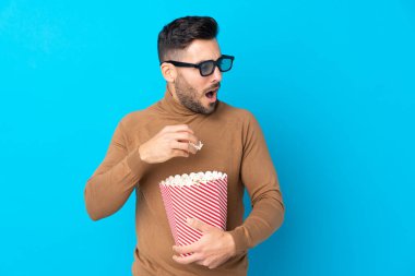 3 boyutlu gözlüklü ve elinde koca bir kova patlamış mısır tutan yakışıklı bir adam.