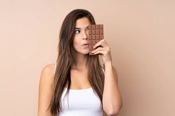 Teenager Dívka Přes Izolované Pozadí Čokoládovou Tabletu Překvapený — Stock fotografie