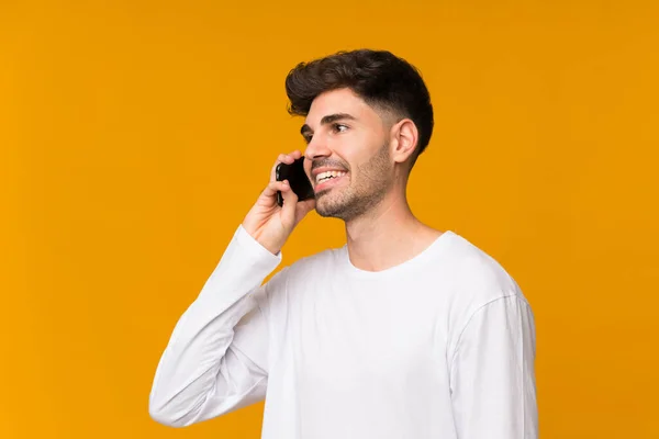 Młody Człowiek Odizolowanym Pomarańczowym Tle Prowadzi Rozmowę Telefonem Komórkowym — Zdjęcie stockowe