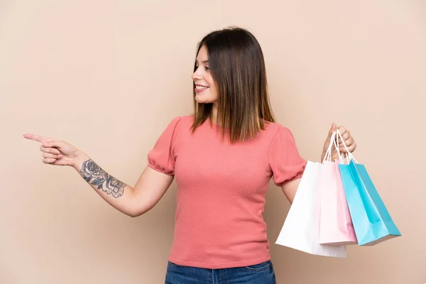 Mujer Joven Con Bolsa Compras Sobre Fondo Aislado Apuntando Hacia —  Fotos de Stock