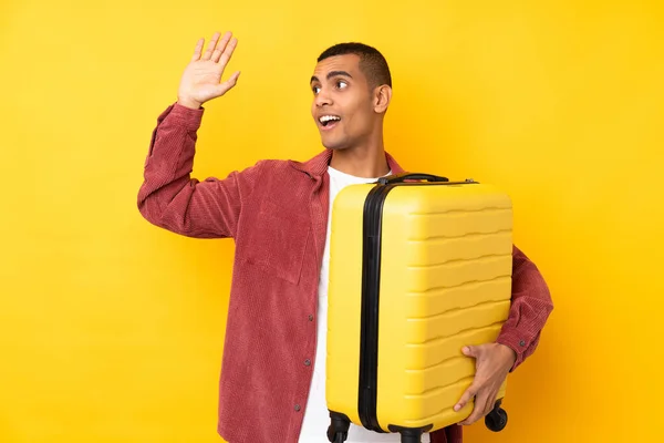 若いですアフリカ系アメリカ人男以上隔離された黄色の背景で休暇で旅行スーツケースと塩漬け — ストック写真
