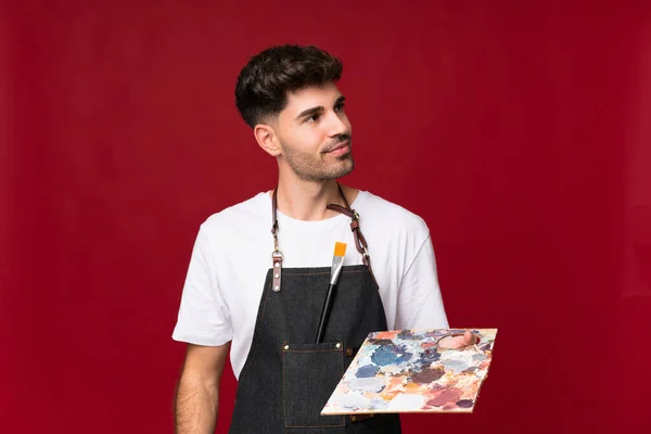 Jovem Sobre Fundo Isolado Segurando Uma Paleta Pensando Uma Ideia — Fotografia de Stock