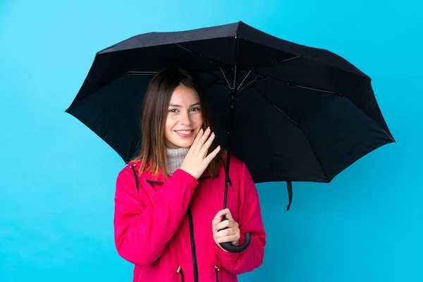 Młoda Kobieta Trzymająca Parasol Nad Odizolowaną Niebieską Ścianą Szepcząc Coś — Zdjęcie stockowe