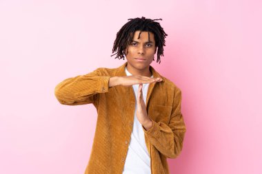 Pembe arka planda kadife ceketli genç Afro-Amerikalı bir adam, jest yapıyor.