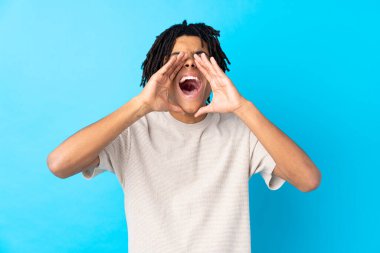 Genç Afro-Amerikalı adam mavi arka planda bağırıyor ve bir şey duyuruyor.