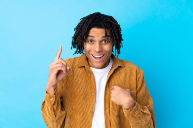 Young African American man with corduroy jacket over isolated blue background with surprise facial expression