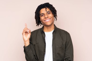 Genç Afro-Amerikan bir adam izole edilmiş arka planda en iyinin işareti olarak parmağını kaldırıyor.