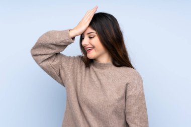 İzole edilmiş mavi arka plan üzerine kazak giyen genç esmer kadın bir şey fark etti ve çözüme niyetlendi.