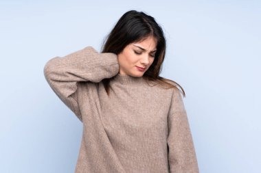 Genç esmer kadın kolyesi olan, izole edilmiş mavi arka plan üzerine süveter giyiyor.