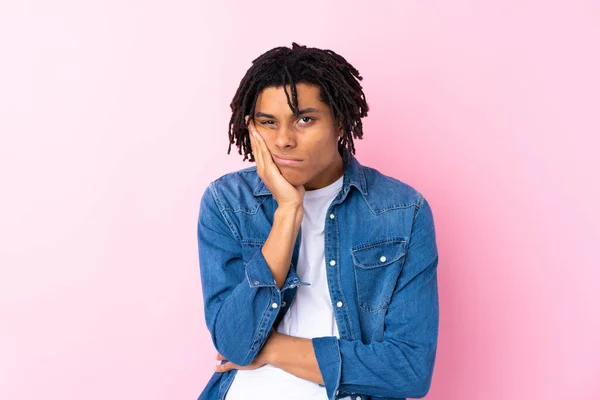 Young African American man with jean shirt over isolated pink background unhappy and frustrated