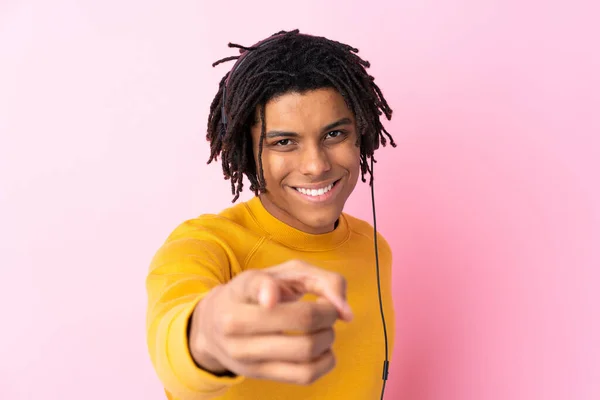 若いですアフリカ系アメリカ人男性リスニング音楽上の隔離されたピンクの壁 — ストック写真