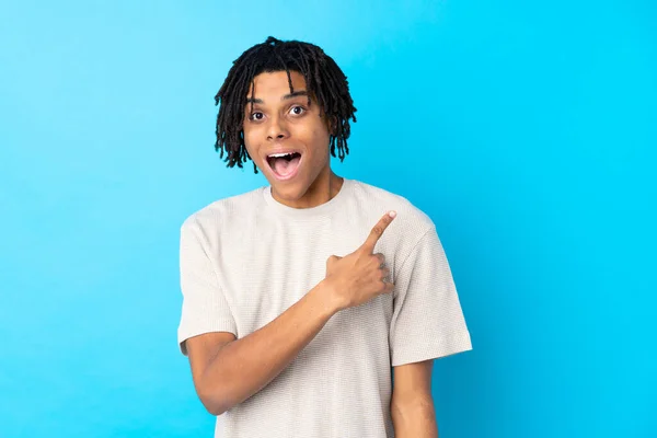 Junger Afroamerikanischer Mann Vor Isoliertem Blauen Hintergrund Überrascht Und Zeigt — Stockfoto