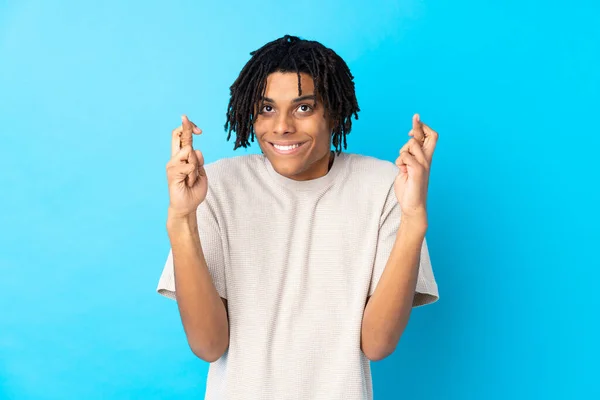 年轻的非裔美国人 越过孤立的蓝色背景 手指头交叉 祝福好运 — 图库照片