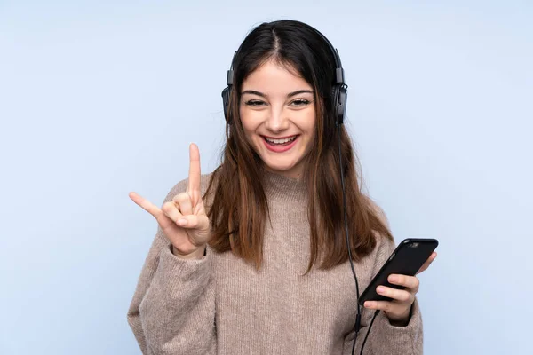 Young Brunette Woman Isolated Blue Background Listening Music Mobile Making — 스톡 사진