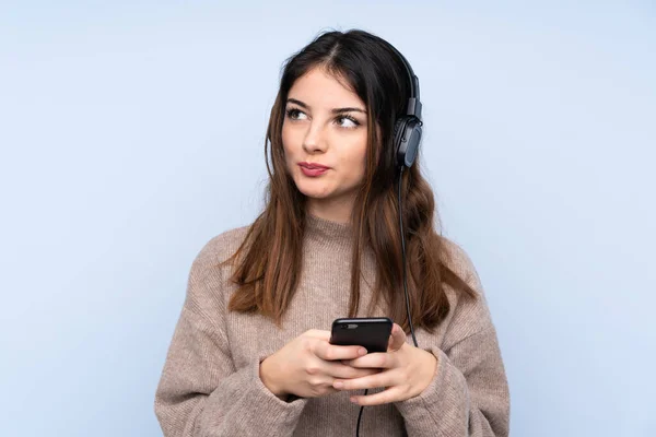 Young Brunette Woman Isolated Blue Background Listening Music Mobile Thinking — 스톡 사진