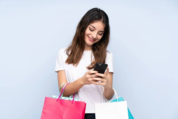 Jovem Morena Sobre Fundo Azul Isolado Segurando Sacos Compras Escrevendo — Fotografia de Stock