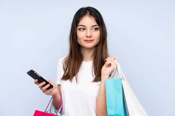 Jovem Morena Sobre Fundo Azul Isolado Segurando Sacos Compras Telefone — Fotografia de Stock