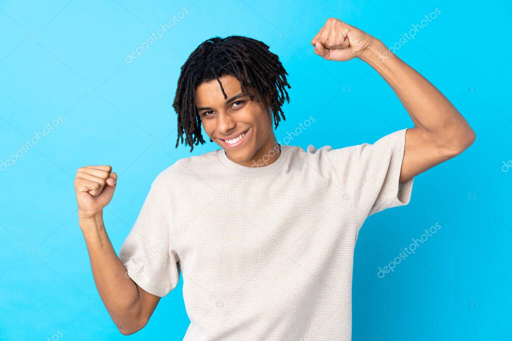 Young African American man over isolated blue background celebrating a victory