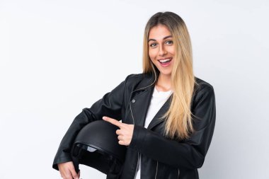 İzole edilmiş beyaz arka plan üzerinde motosiklet kaskı olan genç Uruguaylı kadın, parmağını yana doğru gösteriyor.