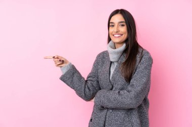 Soyutlanmış pembe arka planda genç esmer bir kadın parmak kaldırıyor.