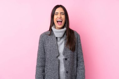 Soyutlanmış pembe arka planda genç esmer kadın ağzı açık bir şekilde öne doğru bağırıyor.