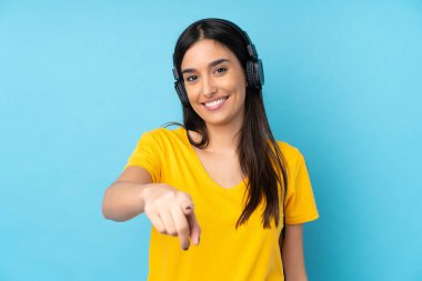 Genç esmer kadın izole edilmiş mavi arka planda müzik dinliyor.