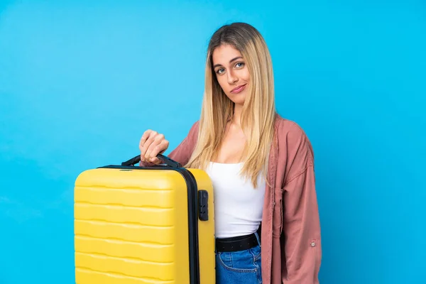 年轻的乌拉圭女人带着旅行箱和不快乐的心情度过了一个孤立的蓝色背景假期 — 图库照片