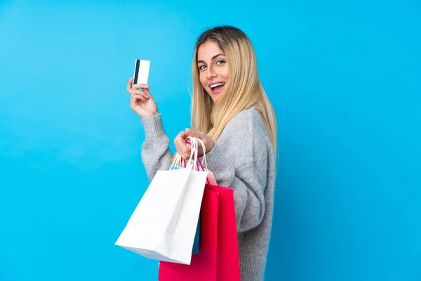 Ung Uruguayansk Kvinna Över Isolerad Blå Bakgrund Innehav Shoppingväskor Och — Stockfoto