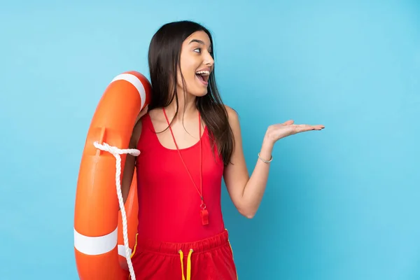 Lifeguard woman over isolated blue background with lifeguard equipment and with surprise facial expression