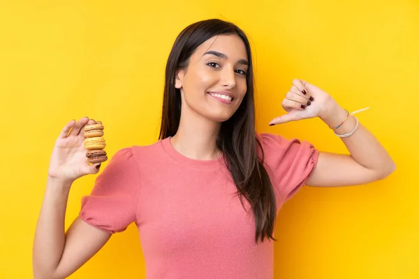 Jovem Morena Sobre Fundo Amarelo Isolado Segurando Macarons Franceses Coloridos — Fotografia de Stock