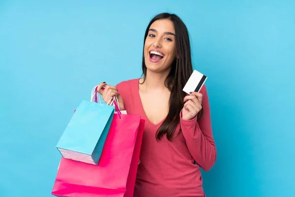 Jonge Brunette Vrouw Geïsoleerde Blauwe Achtergrond Met Winkeltassen Een Creditcard — Stockfoto