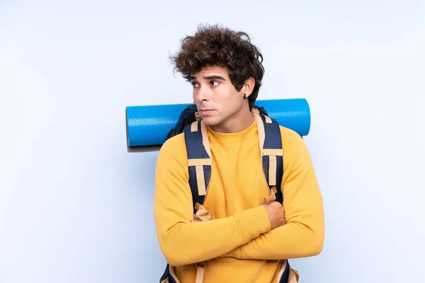 Joven Montañero Con Una Gran Mochila Sobre Fondo Azul Aislado — Foto de Stock