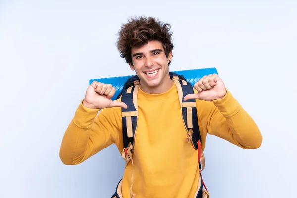 Joven Montañista Con Una Gran Mochila Sobre Fondo Azul Aislado — Foto de Stock