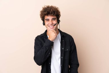 Tele pazarlamacı arka planda kulaklıkla gülerek çalışıyor.