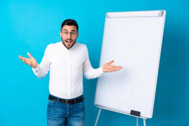Beyaz tahtada sunum yapan iş adamı beyaz tahtada bir sunum yapıyor ve şok olmuş bir ifadeyle