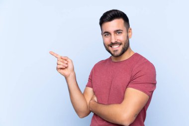 Sakallı, mavi arka planda genç ve yakışıklı bir adam.