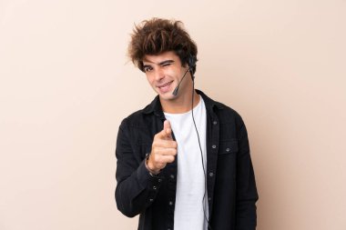 Kulaklıkla çalışan pazarlamacı adam izole edilmiş arka plan noktalarından sana parmak atıyor.