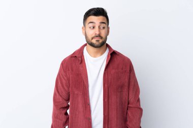 Sakallı, kadife ceket giyen genç yakışıklı bir adam izole edilmiş beyaz arka planda şüpheli hareketler yapıyor.