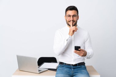 Elinde cep telefonu olan genç bir işadamı sessizlik hareketi yapıyor.