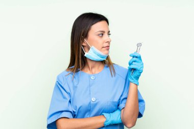 İzole edilmiş yeşil arka plan üzerinde araçları tutan kadın diş hekimi