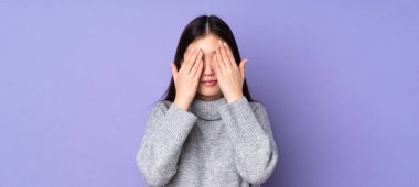 Asyalı genç bir kadın izole edilmiş arka planda gözlerini elleriyle kapatıyor.